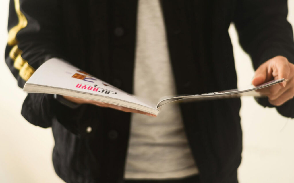 A person flipping through a magazine with blurred text